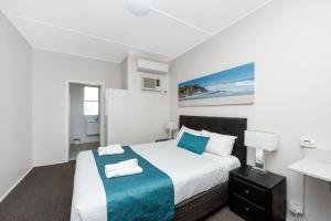 a white bedroom with a bed and a desk at Port Macquarie Motel in Port Macquarie