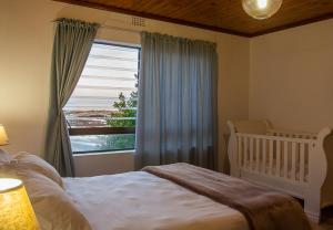 a bedroom with a crib and a large window at Rots en See in Gansbaai