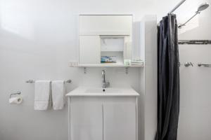 a white bathroom with a sink and a shower at Port Macquarie Motel in Port Macquarie