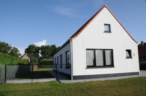 una casa blanca con ventanas negras y una valla en Villa KARIN, en Oostduinkerke