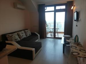 a living room with a couch and a table and a window at Стаи за гости Чайка град Созопол in Sozopol