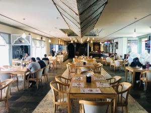 un restaurante con mesas de madera y gente sentada a su lado en Ramee Guestline Hotel, en Mascate