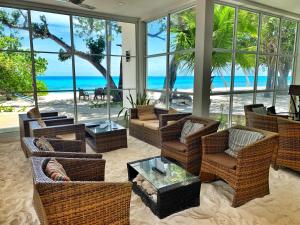 a living room with chairs and tables and the ocean at Athiri Beach Maldives in Dhigurah