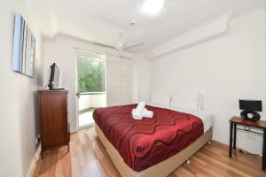 1 dormitorio con 1 cama con manta roja en Founda Gardens Apartments, en Brisbane