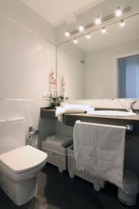 La salle de bains est pourvue de toilettes, d'un lavabo et d'un miroir. dans l'établissement Apartamento Playa Victoria Cadiz, à Cadix