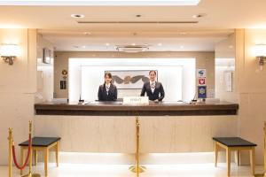 two people standing at a counter in a waiting room at Akasaka Yoko Hotel in Tokyo