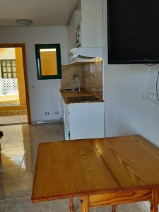 a kitchen with a wooden table and a sink at Apartamento en Caleta Paraíso. in Costa de Antigua