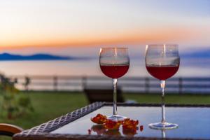 two glasses of red wine sitting on top of a table at Kavos Psarou Villas in Amoudi