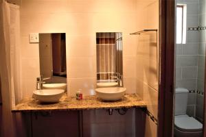 La salle de bains est pourvue de 2 lavabos et de 2 miroirs. dans l'établissement Divundu Guest House, à Divundu