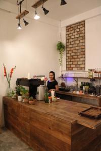 Sacred Lotus - Vegan Café X Hostel في بنوم بنه: امرأة تقف وراء منضدة في مطبخ