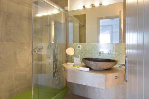 a bathroom with a sink and a glass shower at Santorini Secret Suites & Spa, Small Luxury Hotels of the World in Oia