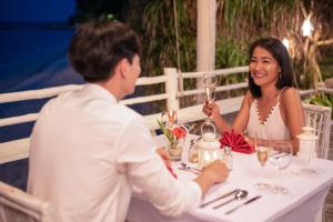 a man and a woman sitting at a table drinking wine at Trikora Beach Club and Resort in Telukbakau