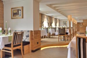 uma sala de jantar com mesas e cadeiras brancas em Hotel Zebru em Solda