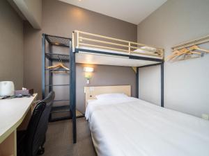 Habitación con cama, escritorio y literas. en Super Hotel Fuji Inter, en Fuji