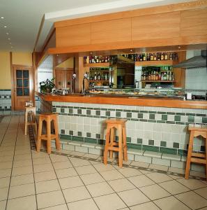 a kitchen with wooden stools and a counter in a restaurant at Hotel Isabel in Briviesca