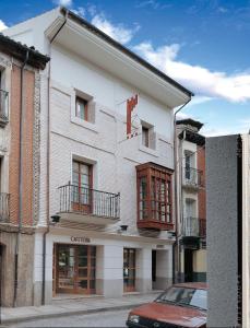 un edificio bianco con un'auto rossa parcheggiata di fronte di Hotel Isabel a Briviesca