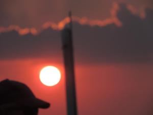 a person wearing a hat in front of a sunset at Pension Achteridyll in Ueckeritz