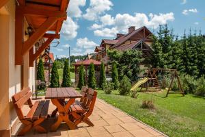 patio con mesa, sillas y parque infantil en Apartamenty Tyrol en Szczawnica