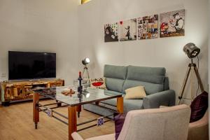 sala de estar con sofá, mesa y TV en Apartamentos Turisticos Moret 11 - 2A, en Cáceres