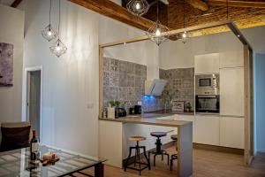 a kitchen with white cabinets and a bar with stools at Apartamentos Turisticos Moret 11 - 2A in Cáceres
