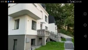 a large white building with a balcony and grass at Apartamentai Veiveriu 16 in Kaunas