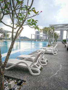 uma fila de espreguiçadeiras brancas ao lado de uma piscina em Gt Home encorp strand residence (alpha ivf ) em Kota Damansara