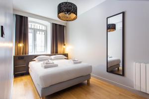 a bedroom with a white bed and a mirror at CMG Canal Saint-Martin - Pierre Levée in Paris