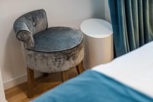 a gray chair sitting in a room next to a bed at Luxury rooms Paula in Split