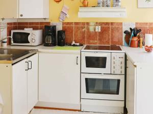 una cucina con armadi bianchi, lavandino e forno a microonde di 4 person holiday home in RKELJUNGA a Orkelljunga