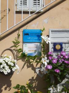 a sign on the side of a building with flowers at Loft al mare in San Lorenzo al Mare