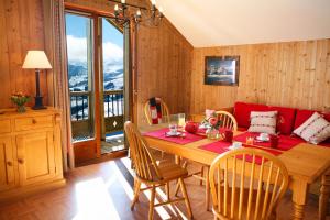 a dining room with a table and a red couch at Résidence Néméa Les Chalets Des Cîmes in La Toussuire