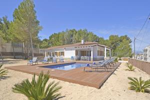 a house with a swimming pool and chairs in the sand at House PINOCHA in Can Picafort