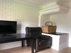 a living room with a table and a chair and a television at Sättraby villa in Norrtälje