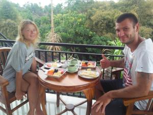 a man and a woman sitting at a table with food at Jero Ratna Homestay in Ubud