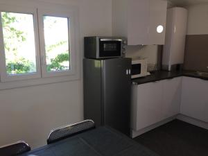 een kleine keuken met een magnetron en een koelkast bij Jm Vacances Serignan in Sérignan