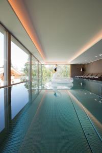 a swimming pool with a tub in a room with windows at Minglers Sportalm - Das Gourmet- und Genießerhotel in Kirchberg in Tirol