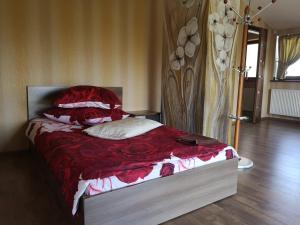 um quarto com uma cama com lençóis e almofadas vermelhas em Abromiškių Sodyba em Elektrėnai