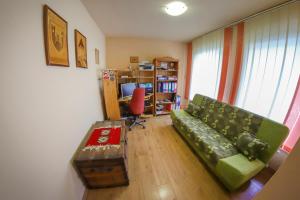 a living room with a green couch and a desk at Apartments Crvena Jabuka in Ključ