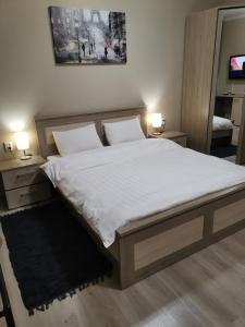 - une chambre avec un lit avec des draps blancs et 2 lampes dans l'établissement Deluxe SPA-Hotel, à Öskemen