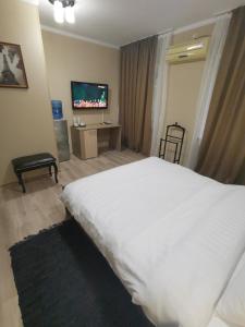 a bedroom with a large white bed and a tv at Deluxe SPA-Hotel in Ustʼ-Kamenogorsk