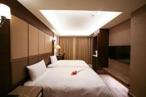 um quarto de hotel com duas camas e uma televisão em Maple Hotel Second Branch em Tainan