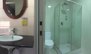 a bathroom with a toilet and a sink and a mirror at De Riau Guesthouse in Bandung