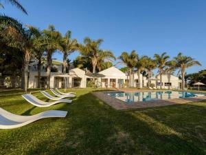 a group of white lounge chairs by a swimming pool at Castleton Unit 73 Plettenberg Bay in Plettenberg Bay