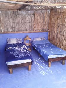 a room with two beds in a straw hut at AliBaba Apartment Hostel Bamboo Rooftop Room in Chefchaouen