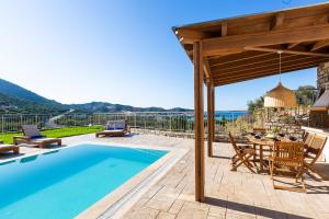 a patio with a pool and a table and chairs at Oraia Eleni Villa, with Pool, BBQ, Playground & SeaViews, By ThinkVilla in Balíon +26 photos