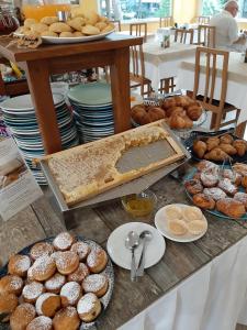 une table garnie de beaucoup de pâtisseries et d'autres pâtisseries dans l'établissement Hotel Kiss, à Cesenatico