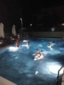 a group of people in a swimming pool at night at Sunset in Plataria
