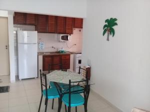 a kitchen with a table and chairs and a white refrigerator at Ap na Avenida da Praia in Caraguatatuba