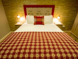 a bedroom with a large bed with a plaid blanket at The World's End - Northampton in Northampton