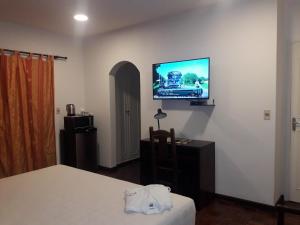 1 dormitorio con 1 cama y TV en la pared en Hotel Casa Jardin en Asunción